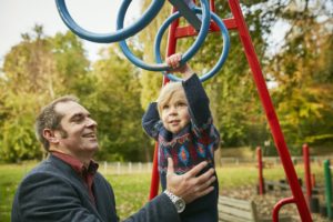 Vater hilft Tochter auf dem Spielplatz