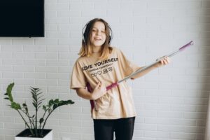 Mädchen spielt Mop-Gitarre beim putzen