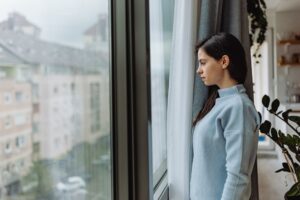 Junge Frau schaut aus dem Fenster dem Regen zu